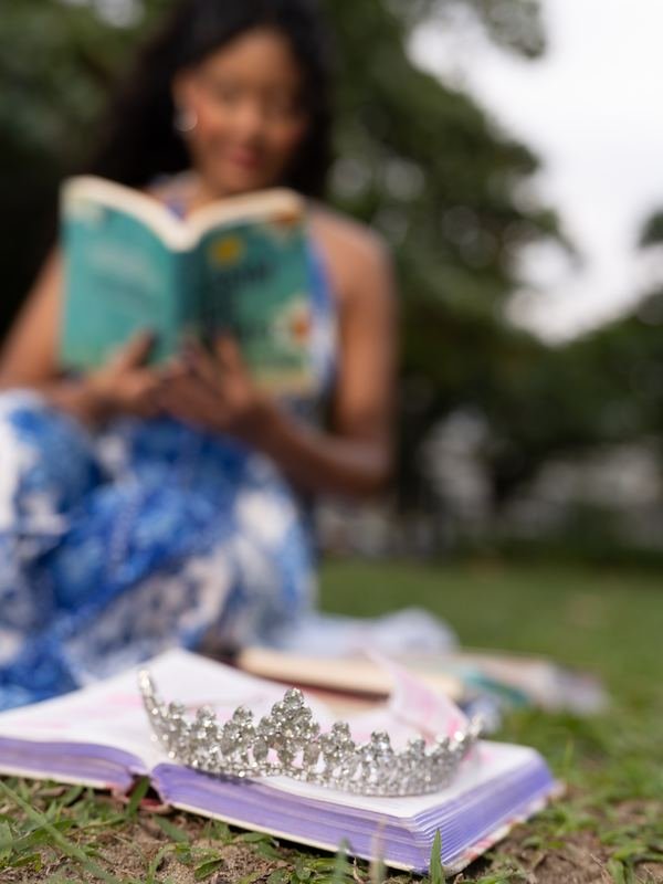 Larissa lendo, com a tiara sobre o livro em primeiro plano